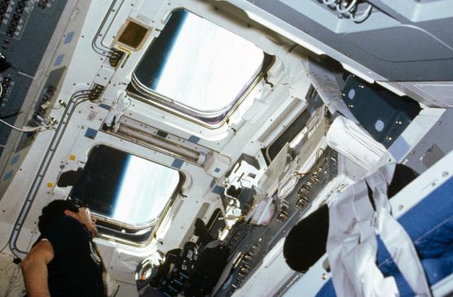 NASA image: Payload specialist Lodewijk van den Berg looks out aft flight deck window