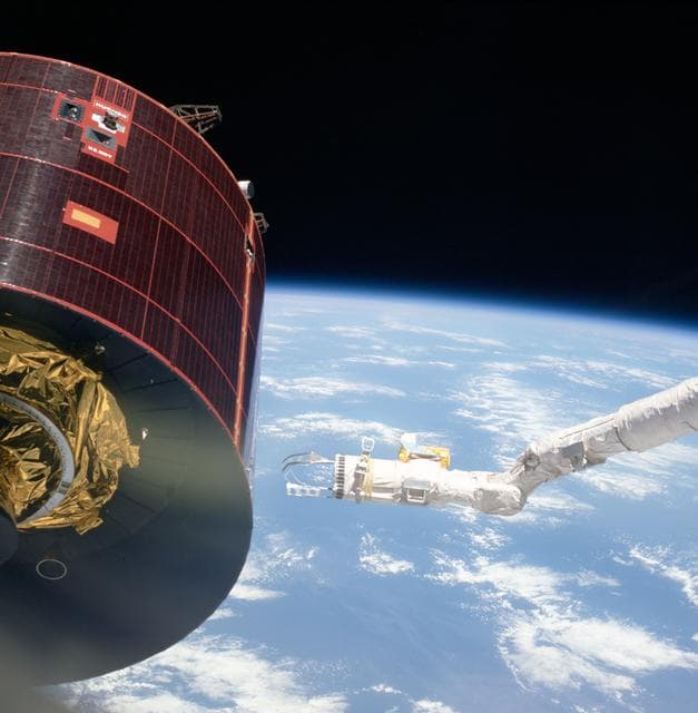 NASA image: End effector of the Discovery's RMS with tools moves toward Syncom-IV
