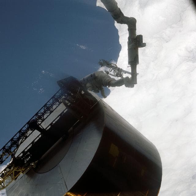 NASA image: Astronaut James van Hoften working with Syncom IV-3 satellite