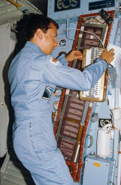NASA image: Payload Specialist Charles Walker with handheld protein growth experiment