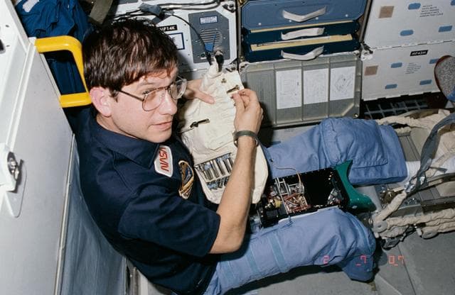 NASA image: Payload specialist Robert Cenker after adjusting DSO equipment