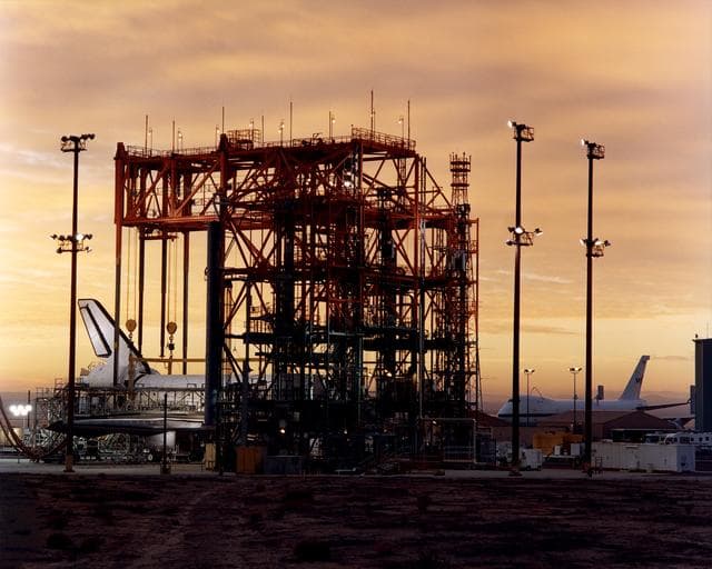 NASA image: STS-92 - Orbiter in Mate-Demate Device (MDD) at sunrise with Shuttle Carrier Aircraft (SCA) in background