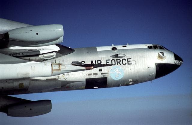 NASA image: The black X-43A rides on the front of a modified Pegasus booster rocket hung from the special pylon under the wing of NASA's B-52B mother ship. The photo was taken during a captive carry flight Jan. 26, 2004 to verify systems before an upcoming launch