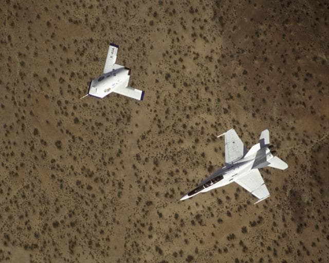 NASA image: X-45A in flight with F-18 #846 chase aircraft, during first GPS-guided weapon demonstration flight