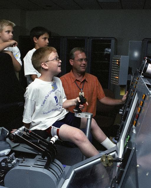 NASA image: Eddie Patterson enjoyed "flying" a C-17 simulator during Take Your Children to Work Day June 22 while Dryden engineer Ken Norlin and other students look on