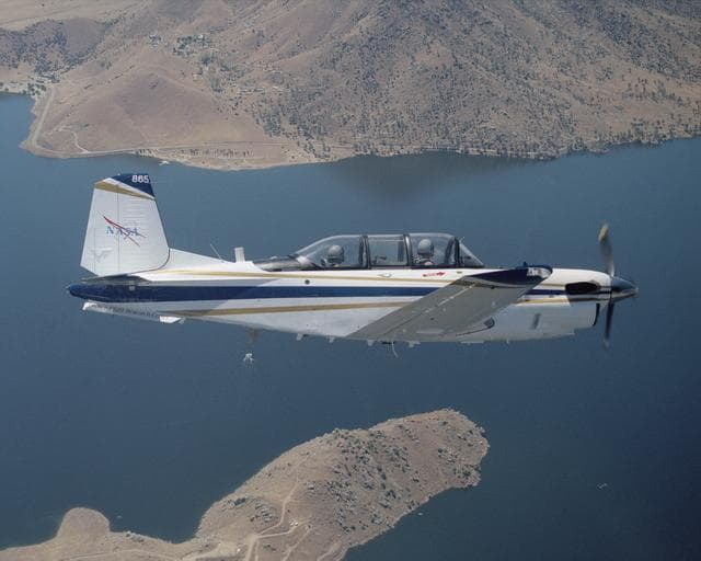 NASA image: A Beech T-34C aircraft used by NASA Dryden Flight Research Center for mission support banks over Lake Isabella in Kern County during a recent flight