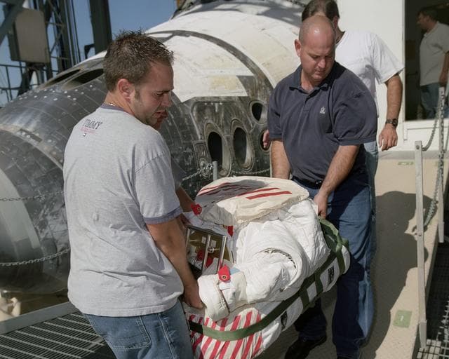 Technicians Ray Smith and Raphael Rodriguez remove one of the Extravehicular Mobility Units from the Space Shuttle Discovery after its landing at NASA Dryden