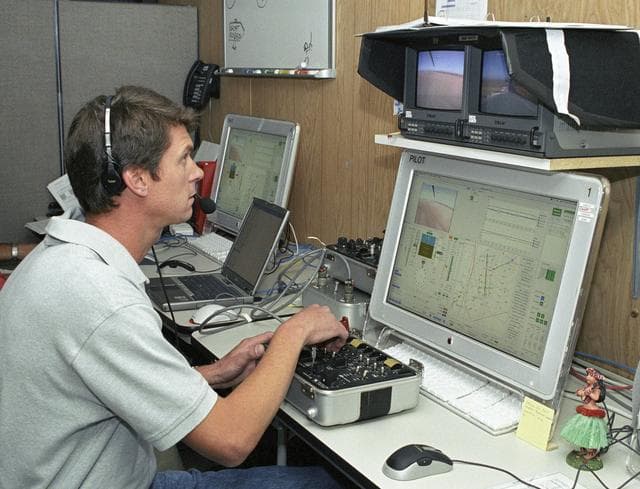 NASA image: AeroVironment pilot Wyatt Sadler controls the Pathfinder-Plus flying wing from a small console, video and computer monitors in the ground station.