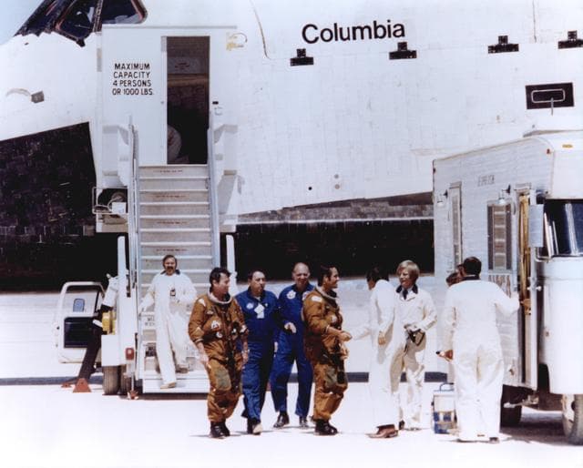 Space Shuttle astronauts John Young and Robert Crippen (in tan space suits) are greeted by members of the ground crew after stepping off the Space Shuttle Columbia after STS-1