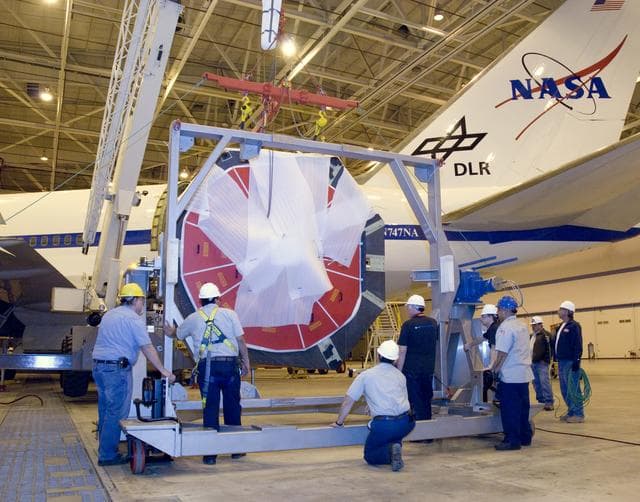 Technicians position the transport cradle as a crane lowers SOFIA's primary mirror assembly into place prior to finish coating of the mirror at NASA Ames