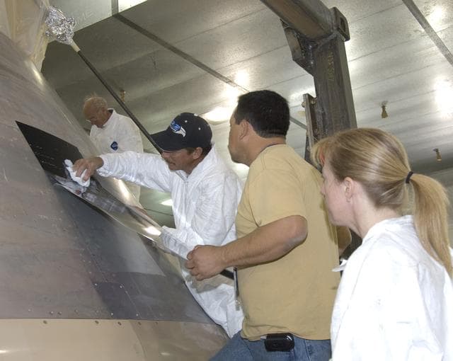 NASA image: Paint shop technicians carefully apply masking prior to painting the Orion full-scale abort flight test crew module in the Edwards Air Force Base paint hangar.