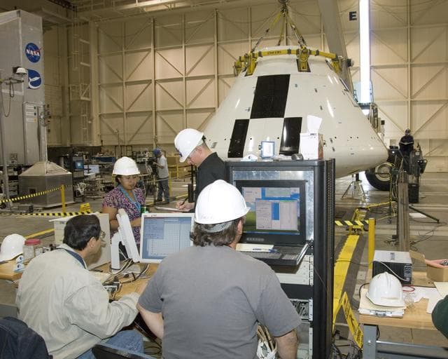 NASA image: Engineers and technicians pore over data during moment-of-inertia testing on the Orion PA-1 Abort Flight Test module in the NASA DFRC Flight Loads Laboratory.