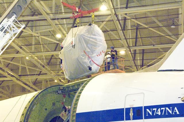 NASA image: echnicians lift SOFIA's primary mirror assembly above NASA's 747SP airborne astronomy aircraft just prior to installation in the telescope cavity