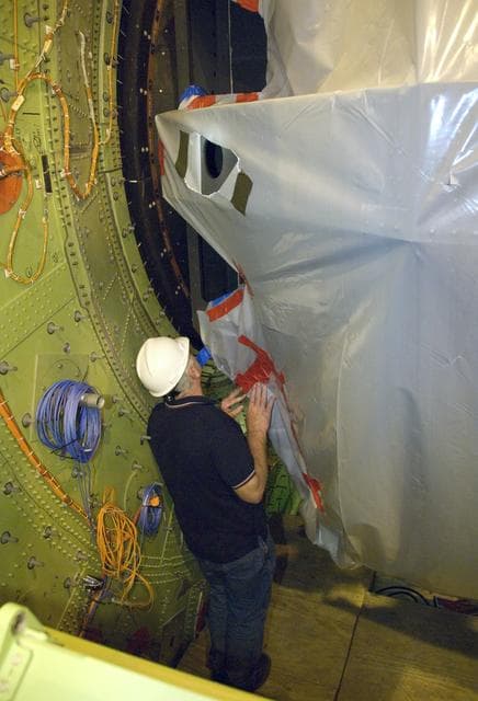 NASA image: A technician guides SOFIA's primary mirror assembly into the aircraft's telescope cavity completing the mirror reinstallation following its initial coating
