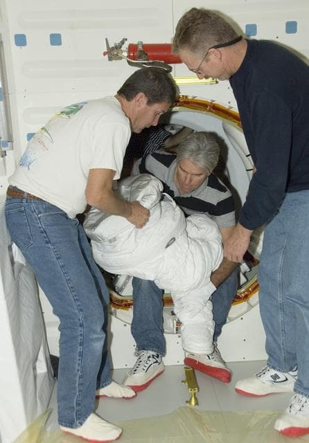 NASA image: Technicians Troy Mann, Mark Shimei and Jim Smodell remove the lower portion of an Extravehicular Mobility Unit (EMU) suit from Endeavour's airlock