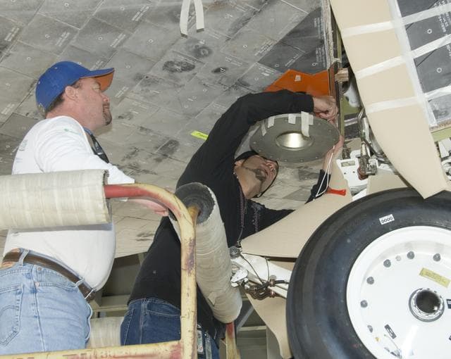 NASA image: Mark Burton and Russell Wazniak attach the forward mount fixture to Shuttle Endeavour for mounting the orbiter to the 747 Shuttle Carrier Aircraft