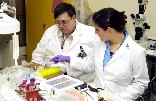 NASA image: KENNEDY SPACE CENTER, FLA. -  From left, Barry Perlman, Pembroke Pines Charter Middle School in Florida, and Valerie Cassanto, Instrumentation Technology Associates, Inc., process one of the experiments carried on mission STS-107. Several experiments were found during the search for Columbia debris. Included in the Commercial ITA Biomedical Experiments payload on mission STS-107 are urokinase cancer research, microencapsulation of drugs, the Growth of Bacterial Biofilm on Surfaces during Spaceflight (GOBBSS), and tin crystal formation.  The latter was sponsored by the Pembroke Pines Charter Middle School.