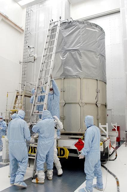 NASA image: KENNEDY SPACE CENTER, FLA. -  Workers in NASA Spacecraft Hangar AE erect a ladder to reach the top of the Space Infrared Telescope Facility (SIRTF), which has been returned to the hangar from the launch pad.   SIRTF will remain in the clean room until it returns to the pad in early August.  One of NASA's largest infrared telescopes to be launched, SIRTF will obtain images and spectra by detecting the infrared energy, or heat, radiated by objects in space.
