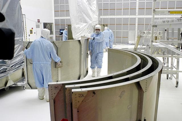 NASA image: KENNEDY SPACE CENTER, FLA. -  Workers in NASA Spacecraft Hangar AE remove sections of the transportation canister from around the Space Infrared Telescope Facility (SIRTF), which has been returned to the hangar from the launch pad.   SIRTF will remain in the clean room until it returns to the pad in early August. One of NASA's largest infrared telescopes to be launched, SIRTF will obtain images and spectra by detecting the infrared energy, or heat, radiated by objects in space.