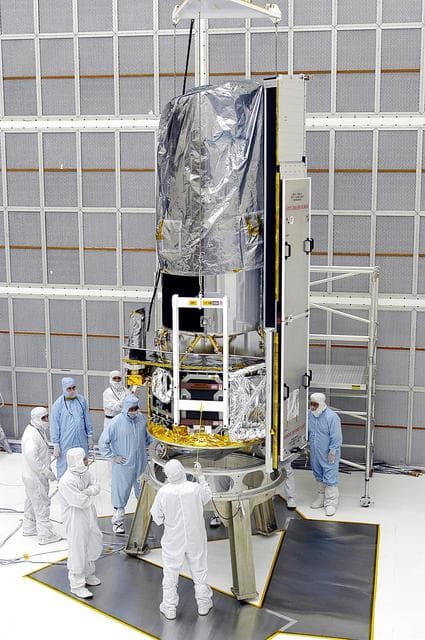 NASA image: KENNEDY SPACE CENTER, FLA. -  Workers in NASA Spacecraft Hangar AE position the Space Infrared Telescope Facility (SIRTF), which has been returned to the hangar from the launch pad, for further processing. SIRTF will remain in the clean room until it returns to the pad in early August. One of NASA's largest infrared telescopes to be launched, SIRTF will obtain images and spectra by detecting the infrared energy, or heat, radiated by objects in space.