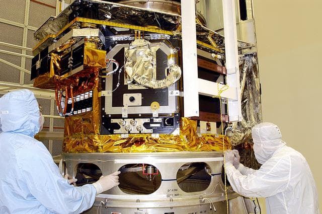NASA image: KENNEDY SPACE CENTER, FLA. -  Workers in NASA Spacecraft Hangar AE check the placement of the Space Infrared Telescope Facility (SIRTF), which has been returned to the hangar from the launch pad for further processing. SIRTF will remain in the clean room until it returns to the pad in early August. One of NASA's largest infrared telescopes to be launched, SIRTF will obtain images and spectra by detecting the infrared energy, or heat, radiated by objects in space.