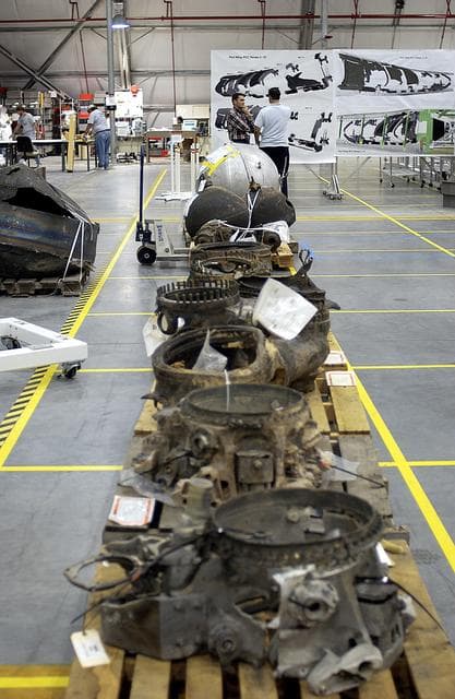 NASA image: KENNEDY SPACE CENTER, FLA. - Large items of Columbia debris fill a long table in the RLV Hangar.  The items shipped to KSC number more than 82,000 and weigh 84,800 pounds or 38 percent of the total dry weight of Columbia.  Of those items, 78,760 have been identified, with 753 placed on the left wing grid in the Hangar.