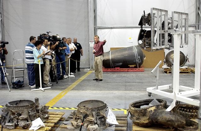NASA image: KENNEDY SPACE CENTER, FLA. - While talking to the media, Shuttle Launch Director Mike Leinbach points to some of the investigative tools in the RLV Hangar, where Columbia debris is being examined.  The items shipped to KSC number more than 82,000 and weigh 84,800 pounds or 38 percent of the total dry weight of Columbia.  Of those items, 78,760 have been identified, with 753 placed on the left wing grid in the Hangar.