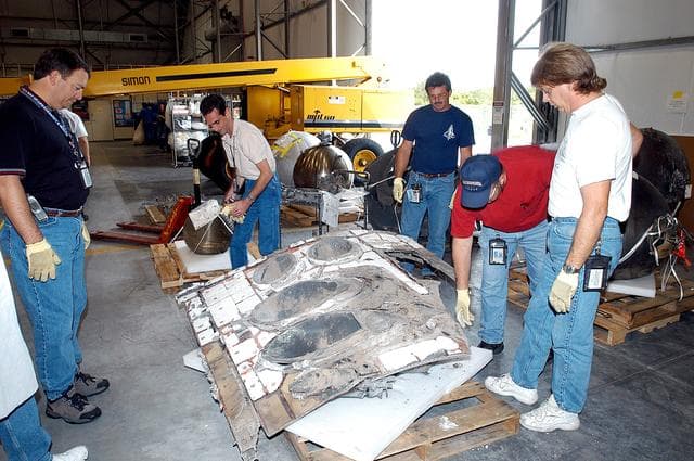 NASA image: KENNEDY SPACE CENTER, FLA. -  Members of the Columbia Reconstruction Project Team work with pieces of debris in the RLV Hangar. The items shipped to KSC number more than 82,000 and weigh 84,800 pounds or 38 percent of the total dry weight of Columbia. Of those items, 78,760 have been identified, with 753 placed on the left wing grid in the Hangar.
