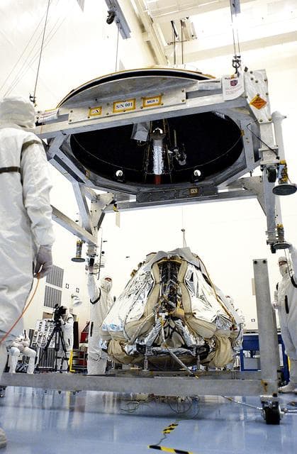 NASA image: KENNEDY SPACE CENTER, FLA. - Workers in the Payload Hazardous Servicing Facility lower the backshell over the Mars Exploration Rover 1 (MER-1).  The backshell is a protective cover for the rover.  NASA's twin Mars Exploration Rovers are designed to study the history of water on Mars. These robotic geologists are equipped with a robotic arm, a drilling tool, three spectrometers, and four pairs of cameras that allow them to have a human-like, 3D view of the terrain. Each rover could travel as far as 100 meters in one day to act as Mars scientists' eyes and hands, exploring an environment where humans can't yet go.  MER-1 is scheduled to launch June 25 as MER-B aboard a Delta II rocket from Cape Canaveral Air Force Station.