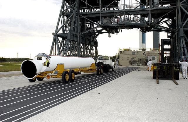NASA image: KENNEDY SPACE CENTER, FLA. - On Launch Complex 17-A, Cape Canaveral Air Force Station, a solid rocket booster is moved into position to raise to vertical and lift up the launch tower.  It is one of nine that will be mated to the Delta rocket to launch Mars Exploration Rover 2. NASA’s twin Mars Exploration Rovers are designed to study the history of water on Mars. These robotic geologists are equipped with a robotic arm, a drilling tool, three spectrometers, and four pairs of cameras that allow them to have a human-like, 3D view of the terrain. Each rover could travel as far as 100 meters in one day to act as Mars scientists' eyes and hands, exploring an environment where humans can’t yet go.  MER-2 is scheduled to launch June 5 as MER-A.  MER-1 (MER-B) will launch June 25.
