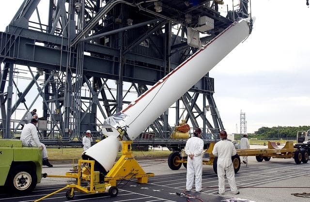 NASA image: KENNEDY SPACE CENTER, FLA. - On Launch Complex 17-A, Cape Canaveral Air Force Station, a solid rocket booster is raised off the transporter.  When vertical, it will be lifted up the launch tower and mated to the Delta rocket (in the background) to launch Mars Exploration Rover 2. NASA’s twin Mars Exploration Rovers are designed to study the history of water on Mars. These robotic geologists are equipped with a robotic arm, a drilling tool, three spectrometers, and four pairs of cameras that allow them to have a human-like, 3D view of the terrain. Each rover could travel as far as 100 meters in one day to act as Mars scientists' eyes and hands, exploring an environment where humans can’t yet go.  MER-2 is scheduled to launch June 5 as MER-A.  MER-1 (MER-B) will launch June 25.