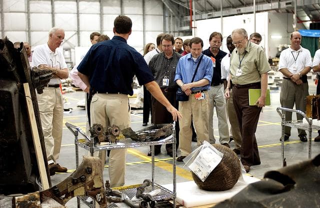 NASA image: KENNEDY SPACE CENTER, FLA. -   Adm. Harold Gehman, far left, chairman of the Columbia Investigation Accident Board, looks at pieces of Columbia debris collected in the KSC RLV Hangar.  Other members of the board accompanied him as part of the ongoing investigation.  Recovery efforts as of May 5 included 82,500 pieces of debris weighing 84,800 pounds, almost 40 percent of the total dry weight of the shuttle.  About 25,000 personnel took part, utilizing almost 1.5 million total man-hours in the recovery effort and involving more than 130 federal, state and local agencies.  The operation was also supported by more than 270 organizations that included businesses and volunteer groups.
