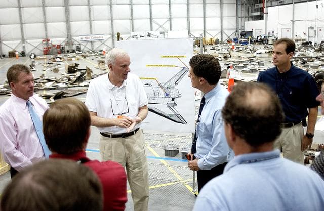 NASA image: KENNEDY SPACE CENTER, FLA. - Adm. Harold Gehman, center, chairman of the Columbia Investigation Accident Board,  talks to U.S. Representative Dave Weldon (right) during the CAIB’s visit to the KSC RLV Hangar.  Left of Gehman is U.S. Representative Tom Feeney.  Gehman and the board visited the Hangar as part of the ongoing investigation.  Recovery efforts as of May 5 included 82,500 pieces of debris weighing 84,800 pounds, almost 40 percent of the total dry weight of the shuttle.  About 25,000 personnel took part, utilizing almost 1.5 million total man-hours in the recovery effort and involving more than 130 federal, state and local agencies.  The operation was also supported by more than 270 organizations that included businesses and volunteer groups.