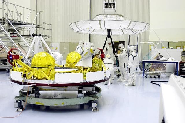 NASA image: KENNEDY SPACE CENTER, FLA. -  Workers in the Payload Hazardous Servicing Facility prepare an overhead crane (background) that will lift the cruise stage, in the foreground, for Mars Exploration Rover 1 (MER-1).  The cruise stage will be moved and integrated with the aeroshell, the entry vehicle.   NASA’s twin Mars Exploration Rovers are designed to study the history of water on Mars. These robotic geologists are equipped with a robotic arm, a drilling tool, three spectrometers, and four pairs of cameras that allow them to have a human-like, 3D view of the terrain. Each rover could travel as far as 100 meters in one day to act as Mars scientists' eyes and hands, exploring an environment where humans can’t yet go.  The MER-1 is scheduled to launch June 25 from Launch Pad 17-A, Cape Canaveral Air Force Station.