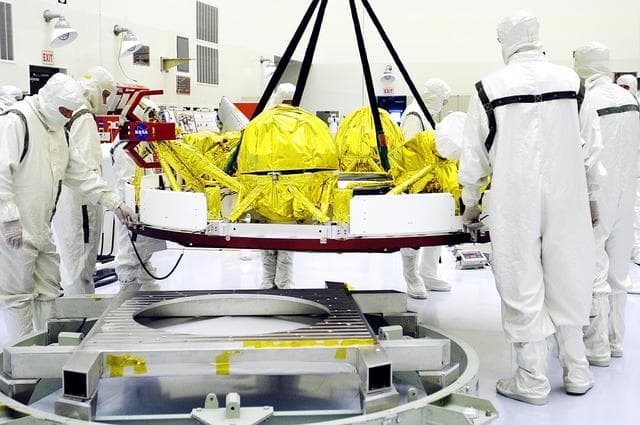 NASA image: KENNEDY SPACE CENTER, FLA. - In the Payload Hazardous Servicing Facility, workers oversee the movement of the cruise stage of Mars Exploration Rover 1 (MER-1).  The cruise stage will be integrated with the aeroshell, the entry vehicle.   NASA’s twin Mars Exploration Rovers are designed to study the history of water on Mars. These robotic geologists are equipped with a robotic arm, a drilling tool, three spectrometers, and four pairs of cameras that allow them to have a human-like, 3D view of the terrain. Each rover could travel as far as 100 meters in one day to act as Mars scientists' eyes and hands, exploring an environment where humans can’t yet go.  The MER-1 is scheduled to launch June 25 from Launch Pad 17-A, Cape Canaveral Air Force Station.