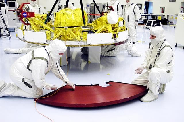 NASA image: KENNEDY SPACE CENTER, FLA. - In the Payload Hazardous Servicing Facility, workers check one of the cruise stage solar panel protective covers on Mars Exploration Rover 1 (MER-1).  The cruise stage will be integrated with the aeroshell, the entry vehicle.   NASA’s twin Mars Exploration Rovers are designed to study the history of water on Mars. These robotic geologists are equipped with a robotic arm, a drilling tool, three spectrometers, and four pairs of cameras that allow them to have a human-like, 3D view of the terrain. Each rover could travel as far as 100 meters in one day to act as Mars scientists' eyes and hands, exploring an environment where humans can’t yet go.  The MER-1 is scheduled to launch June 25 from Launch Pad 17-A, Cape Canaveral Air Force Station.