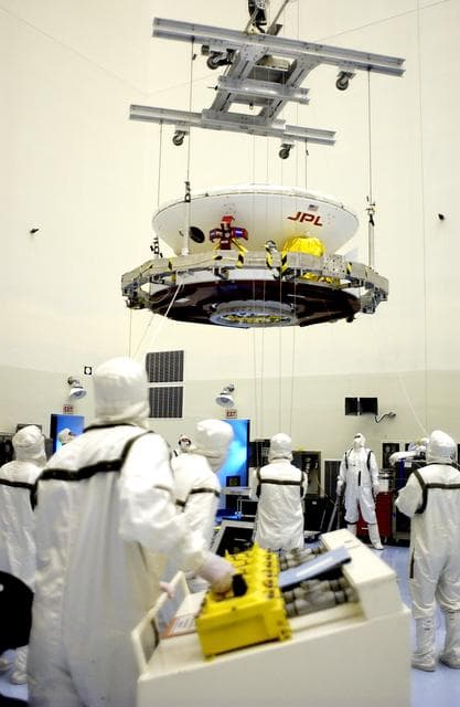 NASA image: KENNEDY SPACE CENTER, FLA. - In the Payload Hazardous Servicing Facility, an overhead crane lifts the Mars Exploration Rover 2 (MER-2) to move it to a spin table.  NASA’s twin Mars Exploration Rovers are designed to study the history of water on Mars. These robotic geologists are equipped with a robotic arm, a drilling tool, three spectrometers, and four pairs of cameras that allow them to have a human-like, 3D view of the terrain. Each rover could travel as far as 100 meters in one day to act as Mars scientists' eyes and hands, exploring an environment where humans can’t yet go.  The MER-2 is scheduled to launch June 5 from Launch Pad 17-A, Cape Canaveral Air Force Station.