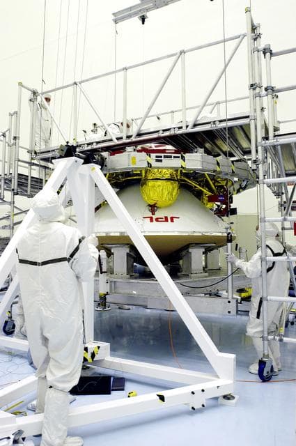 NASA image: KENNEDY SPACE CENTER, FLA. - Workers in the Payload Hazardous Servicing Facility check the mating of the Mars Exploration Rover 1 (MER-1) cruise stage to the lander below it.  NASA's twin Mars Exploration Rovers are designed to study the history of water on Mars. These robotic geologists are equipped with a robotic arm, a drilling tool, three spectrometers, and four pairs of cameras that allow them to have a human-like, 3D view of the terrain. Each rover could travel as far as 100 meters in one day to act as Mars scientists' eyes and hands, exploring an environment where humans can't yet go.  MER-1 is scheduled to launch June 25 as MER-B aboard a Delta II rocket from Cape Canaveral Air Force Station.