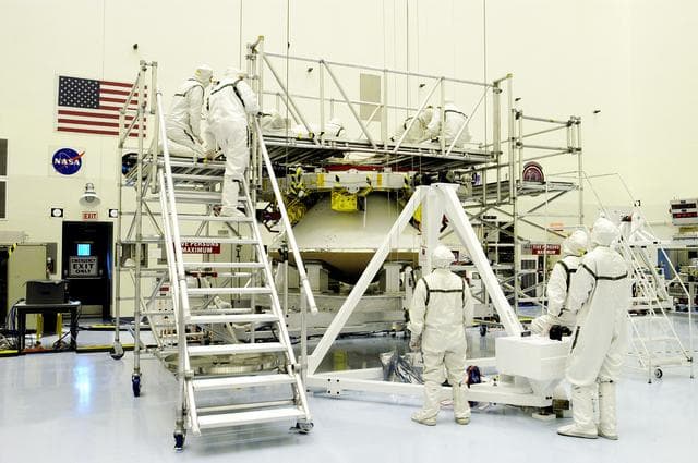 NASA image: KENNEDY SPACE CENTER, FLA. - Workers in the Payload Hazardous Servicing Facility check the mating of the Mars Exploration Rover 1 (MER-1) cruise stage to the lander below it.  NASA's twin Mars Exploration Rovers are designed to study the history of water on Mars. These robotic geologists are equipped with a robotic arm, a drilling tool, three spectrometers, and four pairs of cameras that allow them to have a human-like, 3D view of the terrain. Each rover could travel as far as 100 meters in one day to act as Mars scientists' eyes and hands, exploring an environment where humans can't yet go.  MER-1 is scheduled to launch June 25 as MER-B aboard a Delta II rocket from Cape Canaveral Air Force Station.