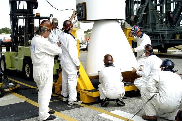 NASA image: KENNEDY SPACE CENTER, FLA. - On Launch Complex 17-B, Cape Canaveral Air Force Station,  workers make adjustments on the solid rocket booster after its lift to vertical.  It is one of nine SRBs that will be mated to the Delta II rocket for the Mars Exploration Rover 1 (MER-1) launch June 25.  NASA’s twin Mars Exploration Rovers are designed to study the history of water on Mars. These robotic geologists are equipped with a robotic arm, a drilling tool, three spectrometers, and four pairs of cameras that allow them to have a human-like, 3D view of the terrain. Each rover could travel as far as 100 meters in one day to act as Mars scientists' eyes and hands, exploring an environment where humans can’t yet go.  MER-2 (MER-A) will launch June 5.