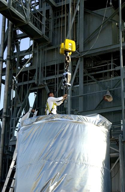 NASA image: KENNEDY SPACE CENTER, FLA. - A  worker on Launch Pad 17-A, Cape Canaveral Air Force Station,  gets ready to attach a cable to the Mars Exploration Rover 2 (MER-2), inside the transport canister.  After it is lifted into the launch tower, it will be mated to the Delta II rocket for launch.  MER-2 is one of NASA's twin Mars Exploration Rovers designed to study the history of water on Mars. These robotic geologists are equipped with a robotic arm, a drilling tool, three spectrometers, and four pairs of cameras that allow them to have a human-like, 3D view of the terrain. Each rover could travel as far as 100 meters in one day to act as Mars scientists' eyes and hands, exploring an environment where humans can't yet go.  MER-2 is scheduled to launch no earlier than June 8 as MER-A.