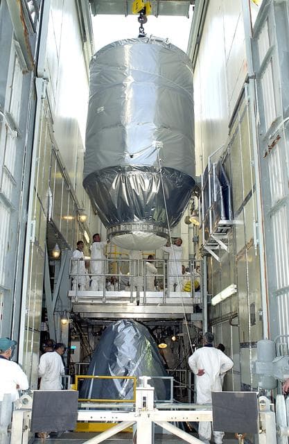 NASA image: KENNEDY SPACE CENTER, FLA. - On Launch Pad 17-A, Cape Canaveral Air Force Station, the Mars Exploration Rover 2 (MER-2), inside the transport canister, is lowered toward the Delta II rocket for mating.  MER-2 is one of NASA's twin Mars Exploration Rovers designed to study the history of water on Mars. These robotic geologists are equipped with a robotic arm, a drilling tool, three spectrometers, and four pairs of cameras that allow them to have a human-like, 3D view of the terrain. Each rover could travel as far as 100 meters in one day to act as Mars scientists' eyes and hands, exploring an environment where humans can't yet go.  MER-2 is scheduled to launch no earlier than June 8 as MER-A.