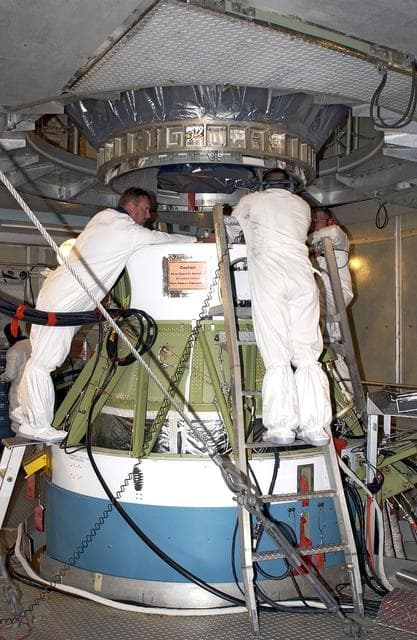 NASA image: KENNEDY SPACE CENTER, FLA. - On Launch Pad 17-A, Cape Canaveral Air Force Station,  workers attach the Mars Exploration Rover 2 (MER-2) , above, to the second stage of the Delta II rocket, below.  MER-2 is one of NASA's twin Mars Exploration Rovers designed to study the history of water on Mars. These robotic geologists are equipped with a robotic arm, a drilling tool, three spectrometers, and four pairs of cameras that allow them to have a human-like, 3D view of the terrain. Each rover could travel as far as 100 meters in one day to act as Mars scientists' eyes and hands, exploring an environment where humans can't yet go.  MER-2 is scheduled to launch no earlier than June 8 as MER-A.