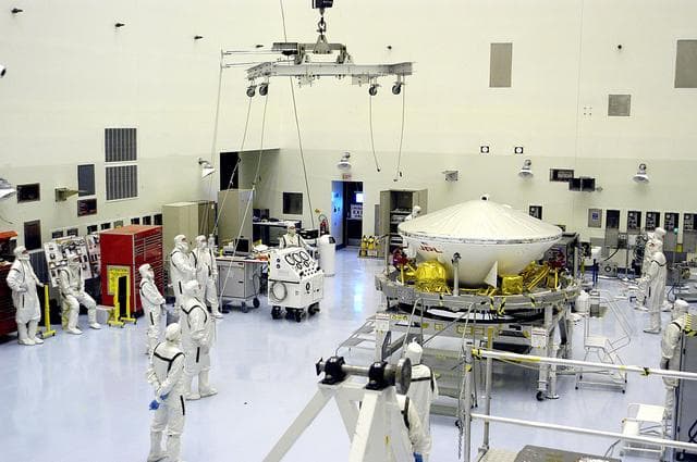 NASA image: KENNEDY SPACE CENTER, FLA. - In the Payload Hazardous Servicing Facility, workers prepare to lift the Mars Exploration Rover-1 (MER-B) onto a spin table during preflight processing of the spacecraft.  The rover is scheduled to launch aboard a Delta II rocket on June 25.  NASA’s twin Mars Exploration Rovers are designed to study the history of water on Mars. These robotic geologists are equipped with a robotic arm, a drilling tool, three spectrometers, and four pairs of cameras that allow them to have a human-like, 3D view of the terrain. Each rover could travel as far as 100 meters in one day to act as Mars scientists' eyes and hands, exploring an environment where humans are not yet able to go. The launch of MER-2 (MER-A) is tentatively set for June 8.