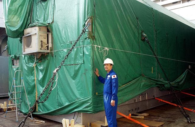 NASA image: KENNEDY SPACE CENTER, FLA. - Astronaut Soichi Noguchi, with the National Space Development Agency of Japan (NASDA), stands next to the Japanese Experiment Module after its arrival at Port Canaveral, Fla.   Built by the Tsukuba Space Center near Tokyo, the pressurized module is the first element of the JEM, Japan’s primary contribution to the space station, to be delivered to KSC. It will enhance the unique research capabilities of the orbiting complex by providing an additional shirt-sleeve environment for astronauts to conduct science experiments. The JEM also includes two logistics modules, an exposed pallet for space environment experiments and a robotic manipulator system that are still under construction in Japan. The various JEM components will be assembled in space over the course of three space shuttle missions.