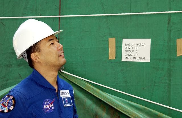 NASA image: KENNEDY SPACE CENTER, FLA. - Astronaut Soichi Noguchi, with the National Space Development Agency of Japan (NASDA), looks at the Japanese Experiment Module after its arrival at Port Canaveral, Fla.   Built by the Tsukuba Space Center near Tokyo, the pressurized module is the first element of the JEM, Japan’s primary contribution to the space station, to be delivered to KSC. It will enhance the unique research capabilities of the orbiting complex by providing an additional shirt-sleeve environment for astronauts to conduct science experiments. The JEM also includes two logistics modules, an exposed pallet for space environment experiments and a robotic manipulator system that are still under construction in Japan. The various JEM components will be assembled in space over the course of three space shuttle missions.