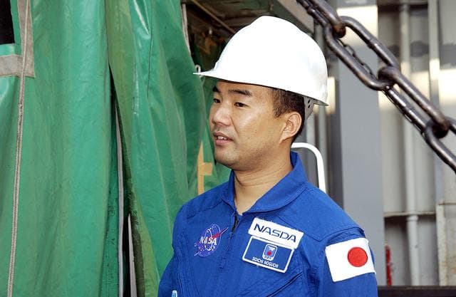 NASA image: KENNEDY SPACE CENTER, FLA. - Astronaut Soichi Noguchi, with the National Space Development Agency of Japan (NASDA), looks at the Japanese Experiment Module after its arrival at Port Canaveral, Fla.   Built by the Tsukuba Space Center near Tokyo, the pressurized module is the first element of the JEM, Japan’s primary contribution to the space station, to be delivered to KSC. It will enhance the unique research capabilities of the orbiting complex by providing an additional shirt-sleeve environment for astronauts to conduct science experiments. The JEM also includes two logistics modules, an exposed pallet for space environment experiments and a robotic manipulator system that are still under construction in Japan. The various JEM components will be assembled in space over the course of three space shuttle missions. .