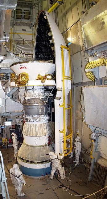 NASA image: KENNEDY SPACE CENTER, FLA. - At Launch Complex 17-A, Cape Canaveral Air Force Station, the first half of the fairing for the Mars Exploration Rover 2 (MER-2) closes in on the spacecraft.  MER-2 is one of NASA's twin Mars Exploration Rovers designed to study the history of water on Mars. These robotic geologists are equipped with a robotic arm, a drilling tool, three spectrometers, and four pairs of cameras that allow them to have a human-like, 3D view of the terrain. Each rover could travel as far as 100 meters in one day to act as Mars scientists' eyes and hands, exploring an environment where humans can't yet go.  MER-2 is scheduled to launch no earlier than June 8 as MER-A, with two launch opportunities each day during the launch period that closes on June 19.