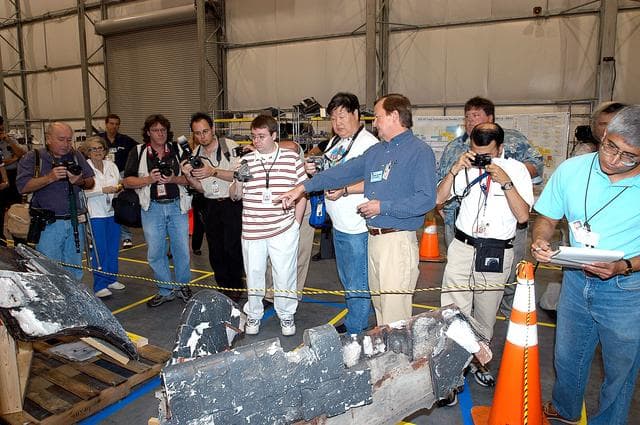 NASA image: KENNEDY SPACE CENTER, FLA. - In the Columbia Debris Hangar,  Shuttle Launch Director Mike Leinbach  points to some of the debris as he explains to the media about activities that have taken place since the Columbia accident on Feb. 1, 2003.  STS-107 debris recovery and reconstruction operations are winding down.  To date, nearly 84,000 pieces of debris have been recovered and sent to KSC. That represents about 38 percent of the dry weight of Columbia, equaling almost 85,000 pounds.