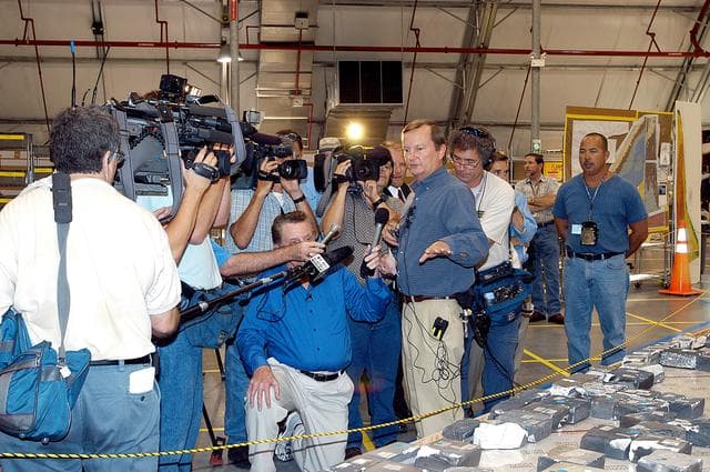 KENNEDY SPACE CENTER, FLA. - In the Columbia Debris Hangar,  Shuttle Launch Director Mike Leinbach  points to some of the tiles recovered from the orbiter as he explains to the media about activities that have taken place since the Columbia accident on Feb. 1, 2003.  STS-107 debris recovery and reconstruction operations are winding down.  To date, nearly 84,000 pieces of debris have been recovered and sent to KSC. That represents about 38 percent of the dry weight of Columbia, equaling almost 85,000 pounds.